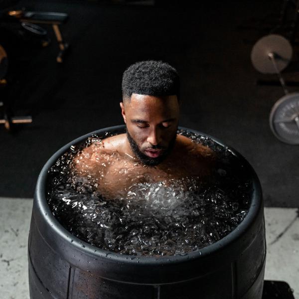 Man immersed in a dedicated black ice barrel cold plunge