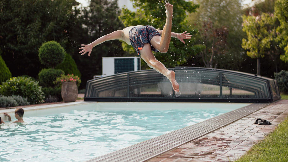 Boy jumping into a backyard swimming pool