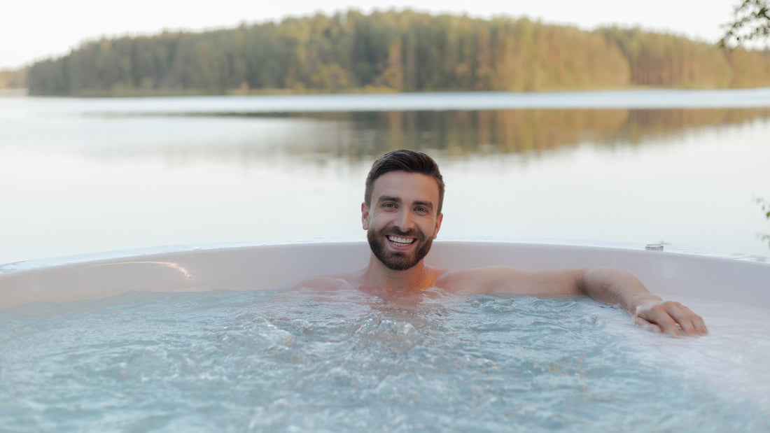 Man relaxing in an outdoor hot tub by a lake