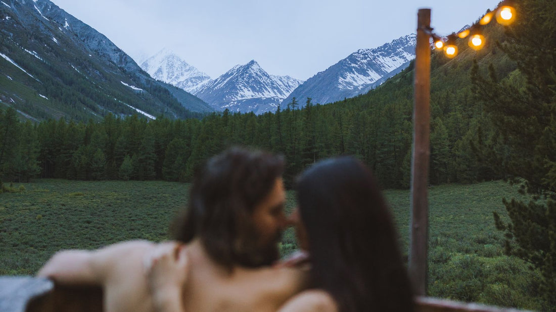 Couple relaxing in an outdoor wooden hot tub with mountain views